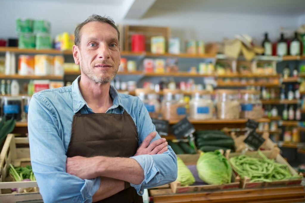pexels-photo-8422730-8422730 Portrait of a male vendor in a Portuguese grocery store with fresh produce.